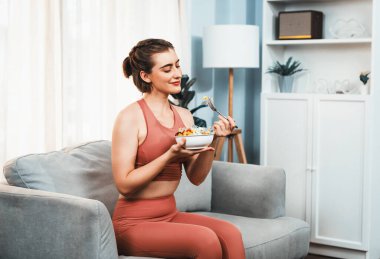 Spor giyimli sağlıklı ve vejetaryen bir kadın bir kase meyve ve sebzeyle. Sağlıklı beslenme ve spor için vejetaryen yaşam tarzı ev konseptinde vücut fiziği.