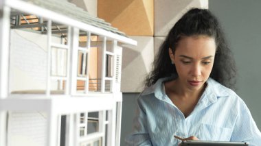 Yetenekli genç, güzel İspanyol mimar mühendis ev yapısını analiz etmek için tablet kullanmaya karar verdi. Profesyonel başarılı iş kadını ev modelini kontrol ediyor ve yatırım yapmaya karar veriyor. Yönlendirici.