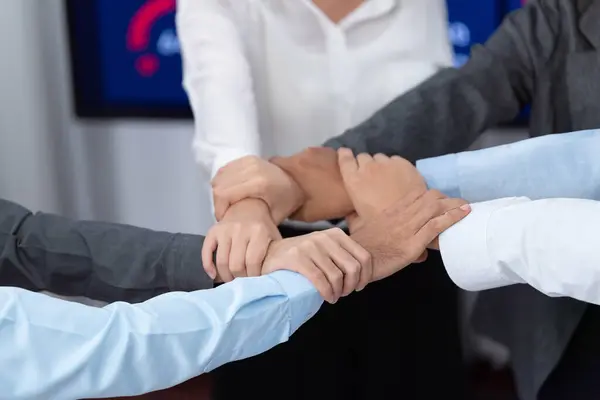 Diverse team of officer workers hold hands in circle, showing solidarity and teamwork in corporate office. Businesspeople form strong community built on integrity and collaboration. Concord