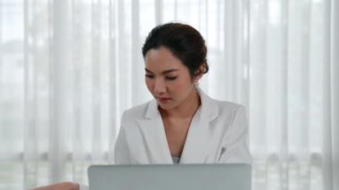 Çalışma masasında internet içeriği için dizüstü bilgisayar kullanan genç bir iş kadını ya da evden çalışan bir sekreter. Canlılık