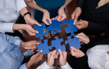 Çeşitli şirket çalışanları, ortaklık ve takım çalışmasını temsil etmek için bulmaca parçalarını birleştirerek ofiste işbirliği yapıyor. Yapboz 'u birleştirerek iş dünyasındaki birlik ve sinerji. Uyum