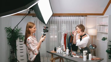 İki kadın nüfuzlu partner sosyal medya veya blog için canlı yayın yapan video klip inceleme derisi çekiyorlar. Kozmetik stüdyosu ışıklandırması olan genç bir kız pazarlama oturumu çevrimiçi yayın yapıyor.