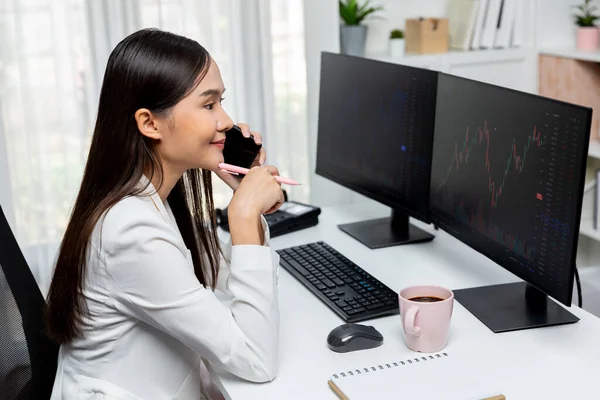 年轻美丽的亚洲女商人笑着打电话给智能手机经纪人 分析现代办公室Pc屏幕上的股票交易市场图表 将高利润投资于财富的概念 Stratagem — 图库照片