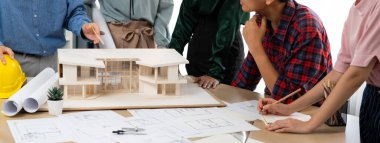 Mimari takım analizi ve ev modeli, plan ve mimari ekipmanlarla toplantı masasında ev inşaatı hakkında beyin fırtınası. Yaratıcı tasarım ve takım çalışması. Filizlenen.