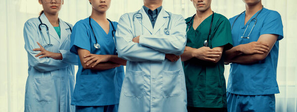 Уверенная и профессиональная команда медицинского персонала стоит в одном ряду как медицинское обслуживание и руководство врачом на больничном фоне. Командная работа ведет к успешному лечению. Panorama Rigid