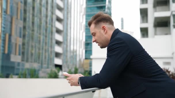 职业商人站在屋顶上用电话与团队聊天 快乐聪明的项目经理在与营销团队沟通的同时 在电话上与摩天大楼视图一起工作 城市E — 图库视频影像