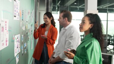 Bir grup iş adamının cam tahtaya yapışkan notlar yapıştırması. Profesyonel iş adamları pazarlama stratejisi geliştirirken cam duvara notlar yapıştırıyor. İş toplantısı. Yönlendirici.