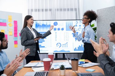 İş adamları TV ekranında başarılı bir sunum veya veri analizi toplantısından sonra kutlama yapıyorlar. Mutlu takım ofis odasında toplanıyor, kutlama jestleriyle işbirliği için tezahürat yapıyorlar. Uyum