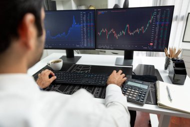 Akıllı tüccar işadamı, modern merkez ofisindeki araştırma pazarında en yüksek kârlı finansal teknolojiye yatırım yaparak bilgisayar üzerinde iki dinamik borsa yatırım ekranını analiz ediyor. Tahmin et..