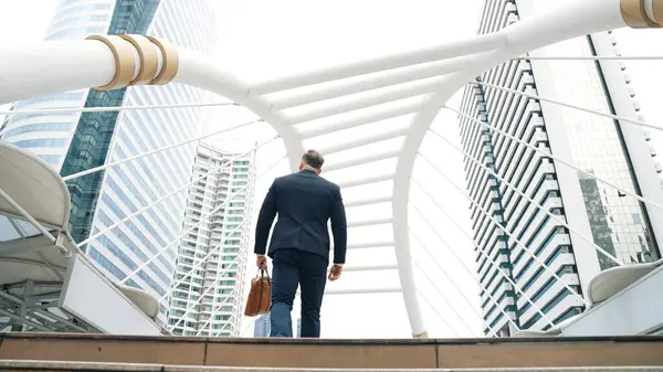 スマートな賢いビジネスマンは 都市の景色に囲まれた階段を歩いています 野心的なプロジェクトマネージャーのバックビューは 近代的な建物を持つ都市で挑戦的な仕事や投資の機会を見つけます ウラベン — ストック写真