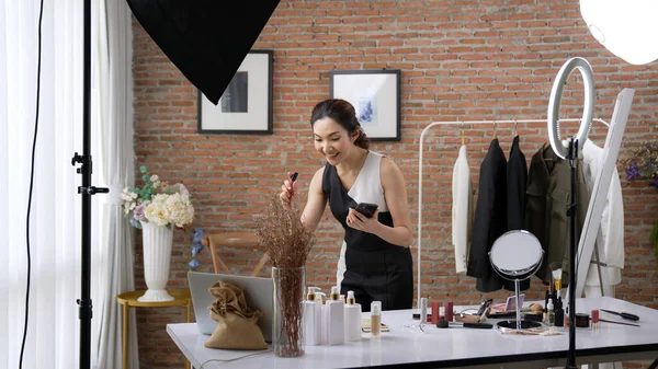 Kadın nüfuzlu kişi canlı yayın yapan video görüntülerini sosyal medya ya da blog üzerinden gözden geçiriyor. Kozmetik stüdyosu ışıklandırmalı mutlu genç kız çevrimiçi pazarlama oturumu yayını için..