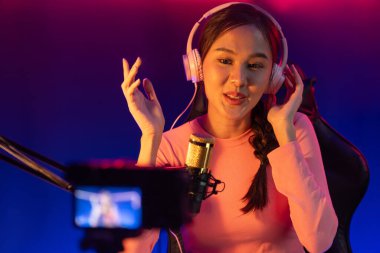 Yaratıcı yayın kanalı sosyal medyada pozitif podcasttaki dinleyicilerle birlikte müziği dinliyor, pastel renkli kulaklıklar takıyor, neon stüdyodaki kameraların mikrofon kayıtlarını kullanıyor. Taktik.