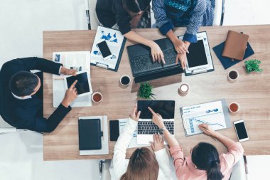 Modern ofisteki iş adamları ve iş kadınlarıyla grup toplantısındaki iş adamlarının en üst düzey görüşü, masada dizüstü bilgisayar, kahve ve belge ile. Kurumsal şirketler uds