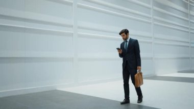 Yetenekli yönetici, iş arkadaşıyla proje hakkında konuşmak için telefon görüşmesi yapıyor. Lider yürürken beyaz arka planda dururken iş ekibini arayıp satışlarla ilgili bilgi verecek. Sevinçli..