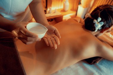 Masör elleri kadının sırtına aroma yağı döküyor. Masözler lüks otellerdeki kaplıca salonundaki müşteriler için yağ masajı prosedürü hazırlıyorlar. Aroma yağı vücut masajı konsepti. Sessiz.