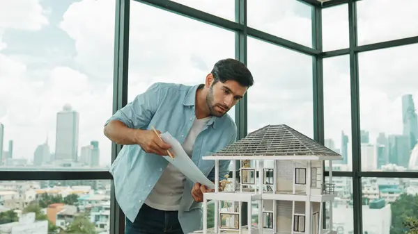 Professional architect engineer comparing between blueprint house model. Businessman decide to invested money in real estate project. Project manager checks house by comparing with plan. Tracery