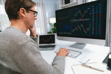 Bilgisayar ve dizüstü bilgisayarı kullanarak, çalışma masasındaki dinamik artırılmış borsa grafiğinin en yüksek kar değerini araştıran bir tüccar, modern ofisteki ekrandaki döviz kuru değerini analiz ediyor. Bireysel.