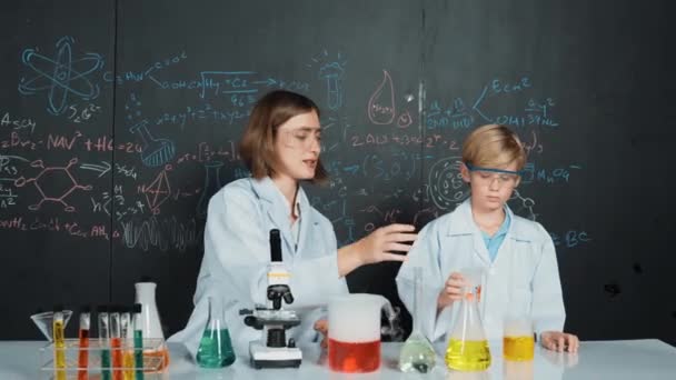 白人老师在科学实验室解释了彩色溶液 专家指导员支持聪明男孩在黑板化学理论的Stem科学课上做实验 Erudition — 图库视频影像