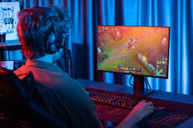 Savaş arenasında çoklu oyunlar takımıyla Moba 'da savaşan genç oyun flamasının sunucu kanalı, neon dijital ışık modern odasındaki arka görüntü ile bilgisayar monitöründe kulaklık takıyor. Toplayıcı.