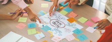 Profesyonel başlangıç grubu zihin haritası kullanarak yaratıcı pazarlama fikrini paylaşıyor. Genç yetenekli iş adamları yapışkan notlar yazarken beyin fırtınası planı yapıyorlar. Eline odaklan. - Yakın çekim. Değiştirilmiş.