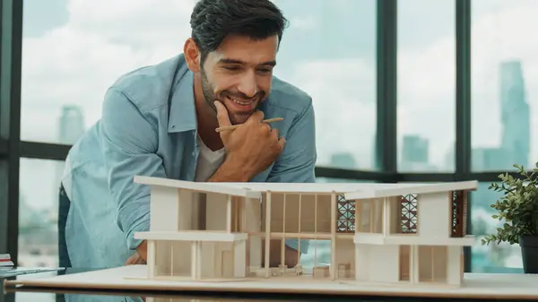 Smart civil architect engineer looking while planing design house construction with blueprint, house model and architectural equipment. Designer measuring and inspecting house model. Tracery