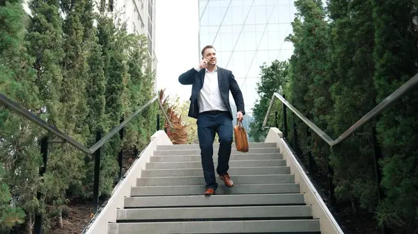 Happy businessman walking down stair and calling manager by using smart phone. Top view of manager talking marketing team and planning financial strategy by telephone while going down stair. Urbane.
