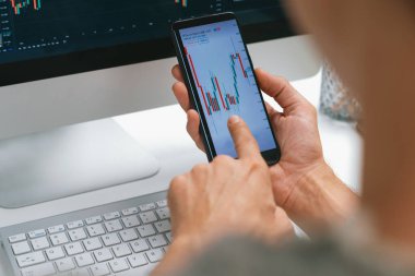 Akıllı borsa yatırımcıları ekranda akıllı telefon ile piyasa borsasını işaret ederek dizüstü bilgisayarın yanı sıra en yüksek dinamik yatırım oranını göstererek, modern işyerindeki veri planlamasına odaklanıyorlar. Bireysel.