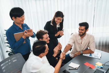 Çeşitli ofis çalışanları stratejik iş pazarlama toplantısı üzerine anlaşma yaptıktan sonra el sıkışıyor. Takım çalışması ve olumlu tutum verimli ve destekleyici bir iş yeri yaratır. Tedbirli