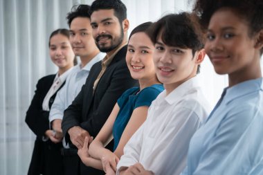 Mutlu ve gülümseyen çok ırklı ofis çalışanı, sinerjiyi ve ticari başarı için işbirliğini destekleyen bir kuyrukta el ele tutuşuyor. Modern işyerinde çeşitli profesyonel ofis çalışanları arasında bağ var. Uyum