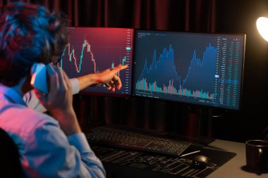 Genç yatırımcı borsacı brokerla birlikte arıyor. Yatırım değişimlerini gösteren bir monitörle güncel piyasa grafiğinde gerçek zamanlı olarak en yüksek karı elde etmek için. Toplayıcı.