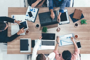 Modern ofisteki iş adamları ve iş kadınlarıyla grup toplantısındaki iş adamlarının en üst düzey görüşü, masada dizüstü bilgisayar, kahve ve belge ile. Kurumsal şirketler uds