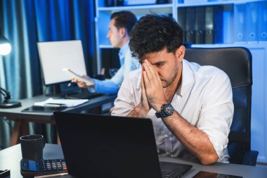 Baş ağrısı olan stresli iş arkadaşı gece vakti yeni bir proje üzerinde çalışıyor, e-posta bekliyor kazanma teklifi veren müşteri firması için geri gönderiliyor. Neon mavi ışık modern ofis üzerinde çalışma kavramı. Satılabilir.