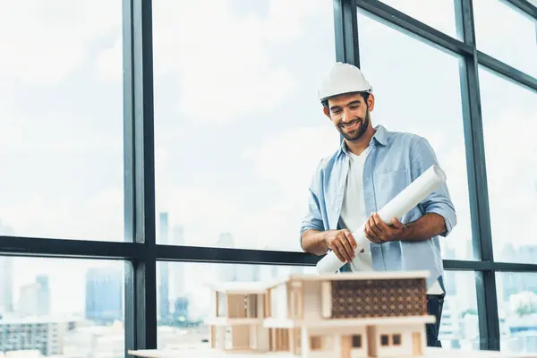 Smart civil engineer standing, walking while looking at house model and architectural equipment. Engineer with safety helmet standing near city view while standing near building model. Tracery.