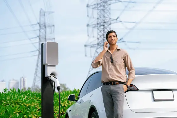 Man Praten Aan Telefoon Tijdens Het Opladen Van Autobatterij Laadstation — Stockfoto