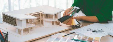 Yetenekli iç mimarın kırpılmış bir görüntüsü, renk örnekleriyle karşılaştırarak ev modeli için uygun zemin malzemesi seçer. Yaratıcı çalışma ve tasarım konsepti. Değiştirilmiş.