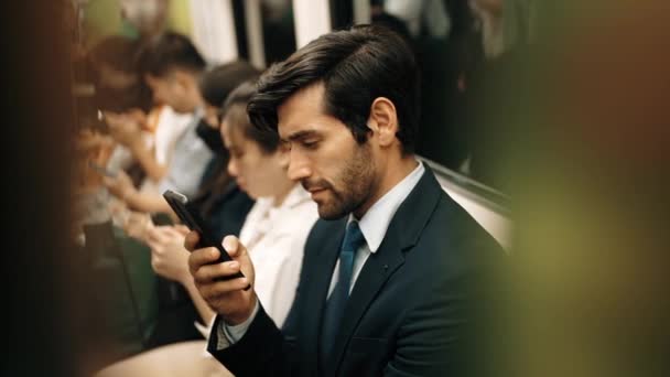 スマートなスマートなビジネスマンは 携帯電話を見たり 電車の中で座っている間にソーシャルメディアをプレイしたりします 魅力的なプロジェクトマネージャーは ラッシュアワーで公共交通機関を使用して場所を動作します エクササイズ — ストック動画