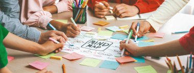 Yaratıcı iş adamları, zihin haritalama kullanarak pazarlama stratejisi ve iş planı hakkında beyin fırtınası yapıyorlar. Girişim ekibi kağıda yazmak için birlikte çalışır. Eline odaklan. - Yakın çekim. Değiştirilmiş.