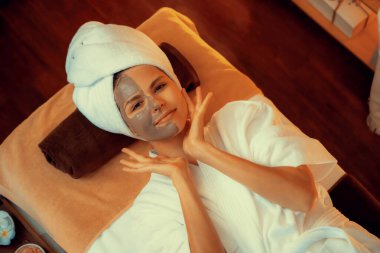 Kaplıca salonunun sakin atmosferi, üst düzey kadın müşteri sıcak mum ışığında kömür kömürü yüz kremi masajıyla kendini yenilemeye çalışıyor. Yüz bakımı ve güzellik konsepti. Sessiz.