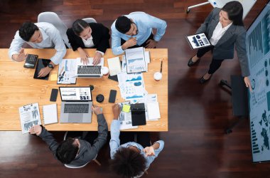 Modern toplantı odasındaki TV ekranında veri analizi paneliyle üst görünüm iş sunumu. İş adamlarının iş pazarlama stratejisini planlamak için beyin fırtınası yapması ya da birlikte çalışması. Uyum