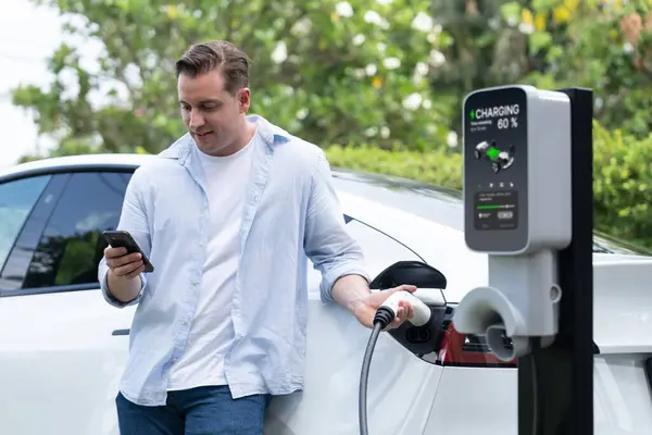现代生态友好型电动汽车充电站向电动汽车充电 利用创新电动汽车技术跟踪能源使用情况 优化智能手机充电 — 图库照片