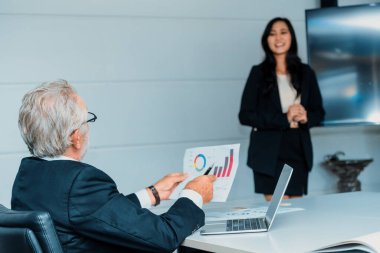 Toplantı odasında genç bir iş kadınının finansal sunumunu dinleyen kıdemli yönetici. Sekreter patrona rapor verir. İş yeri konsepti. uds
