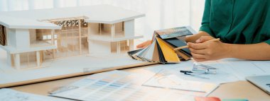 Yetenekli iç mimarın kırpılmış bir görüntüsü, renk örnekleriyle karşılaştırarak ev modeli için uygun zemin malzemesi seçer. Yaratıcı çalışma ve tasarım konsepti. Değiştirilmiş.