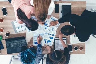 Modern ofisteki iş adamları ve iş kadınlarıyla grup toplantısındaki iş adamlarının en üst düzey görüşü, masada dizüstü bilgisayar, kahve ve belge ile. Kurumsal şirketler uds