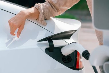 Kapalı el, şehrin park alanındaki şarj istasyonundan elektrikli araba aküsünü şarj etmek için EV şarj aleti yerleştirdi. Sürdürülebilir çevre dostu şehir yolculuğu için şarj edilebilir EV araba. Yararlı