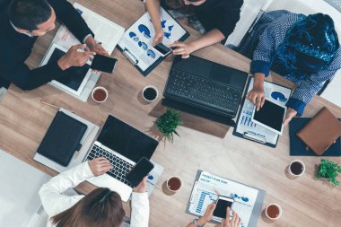 Modern ofisteki iş adamları ve iş kadınlarıyla grup toplantısındaki iş adamlarının en üst düzey görüşü, masada dizüstü bilgisayar, kahve ve belge ile. Kurumsal şirketler uds