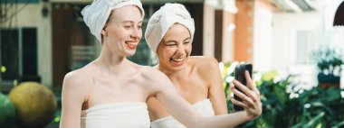 Beyaz havluyla güzel ciltli bir çift güzel kadın açık havada barışçıl doğal çevreyle çevrili bir şekilde fotoğraf çekiyorlar. Güzellik ve sağlıklı spa konsepti. Huzur.