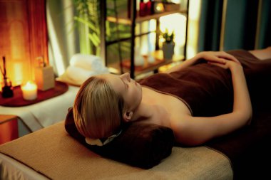 Beyaz kadın müşteri stres önleyici spa masajının keyfini çıkarıyor ve lüks otel ya da otelde sıcak mum ışığında güzellik teniyle eğleniyor. Sessiz.