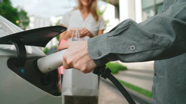 Genç çift yazın yeşil sürdürülebilir evde EV elektrikli araba ile seyahat ederken, yeşil temiz yeniden şarj edilebilir elektrikli araç iç organları ile kentsel sürdürülebilirlik yaşam tarzını gösteriyor