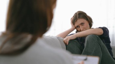 Psikologla ruh sağlığı terapisi gören üzgün travma sonrası stres bozukluğu olan bir kadın. Yaşam sonrası depresyon veya keder. Hayal kırıklığına uğramış genç bir kadın klinikteki duygular hakkında prim psikoloğuyla konuşuyor.