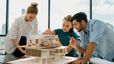 Akıllı mimar takımı ev tasarımı hakkında tartışırken yakışıklı erkek işçi dizüstü bilgisayar kullanarak fikir sunuyor. Profesyonel mühendis paylaşımı, beyin fırtınası tasarımı. İş tasarımı. İzleme